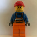 fig-000781 – Construction Worker, Orange Overalls over Blue Sweater, Red Hard Hat, Stubble