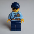 fig-002100 – Policewoman, Bright Light Blue Shirt with Radio and Badge, Dark Blue Legs, Dark Blue Cap with Hair, Sunglasses