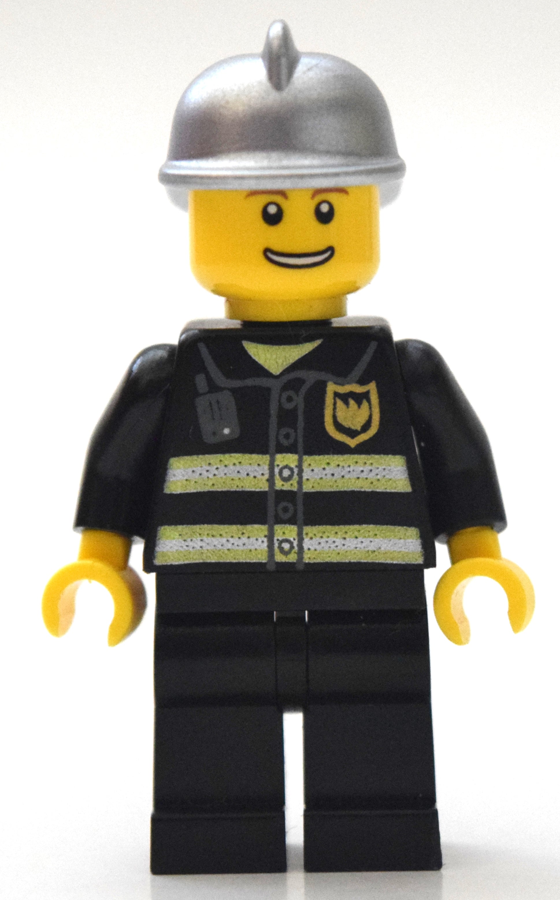 fig-008050 – Fireman, Black Fire Jacket with Reflective Stripes, Radio, and Badge, Silver Helmet