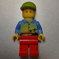 fig-008884 – Man, Medium Blue Shirt with Palm Trees and Sunset, Red Legs, Lime Cap