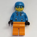 fig-009825 – Woman, Dark Azure Ski Jacket, Orange Legs, Dark Azure Helmet, Snow Goggles