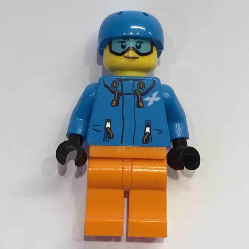 fig-009825 – Woman, Dark Azure Ski Jacket, Orange Legs, Dark Azure Helmet, Snow Goggles